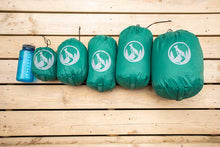 Shows all sizes of dog sleeping bag in included stuff sack next to nalgene water bottle for size comparison.